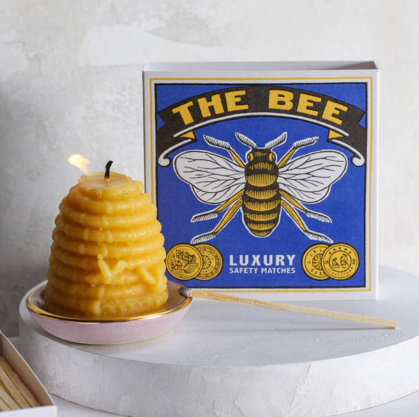 The bee match box with a lit beeswax candle