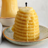 Big beehive candle thats been lit on a dew collection dish
