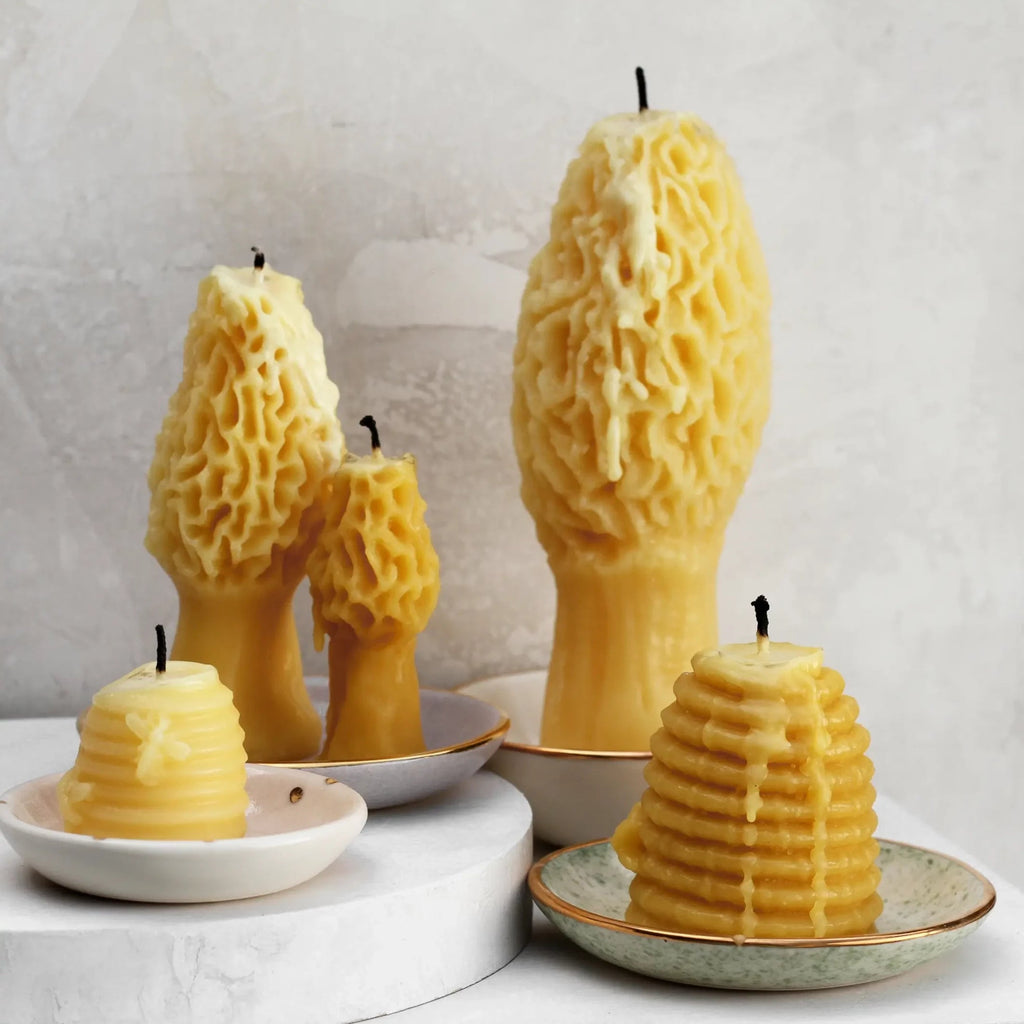 Group of beeswax candles that have been lit on trinket dishes